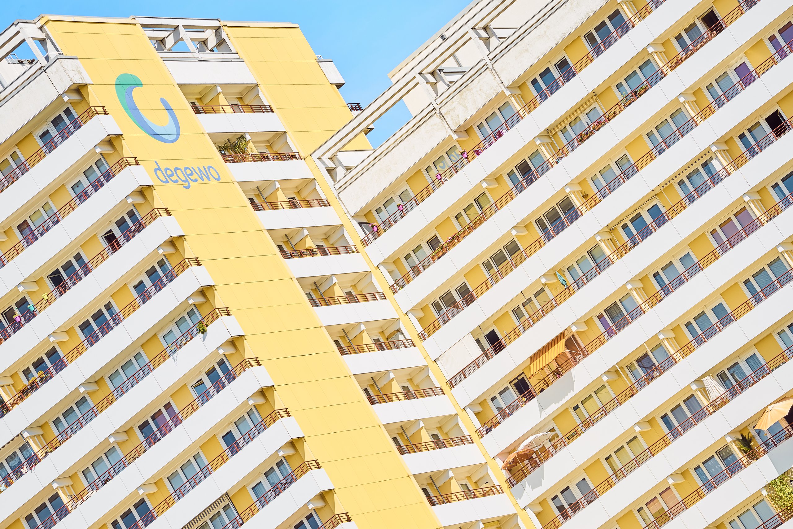 Springpfuhl Berlin, degewo Wohnhochhäuser: Zwei gelb-weiße Hochhäuser mit vielen Balkonen und Fenstern unter blauem Himmel